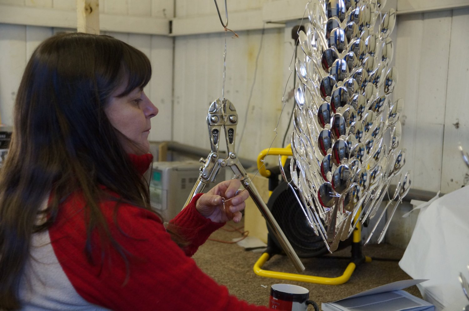 A member of the team wiring work onto the plating frames at Portland Works