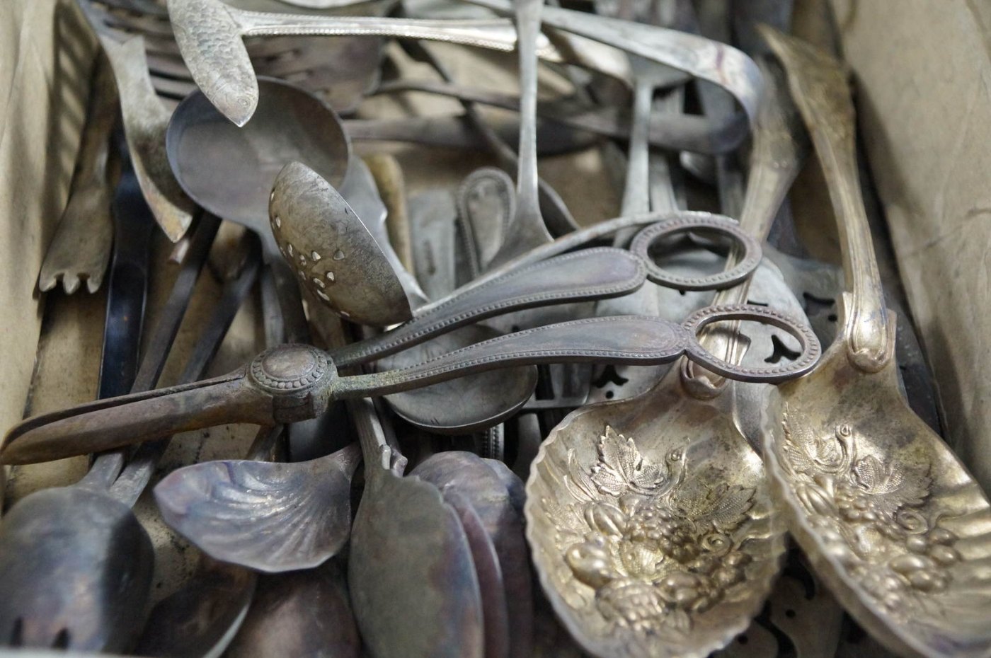 A box of tarnished, worn silverware before restoration