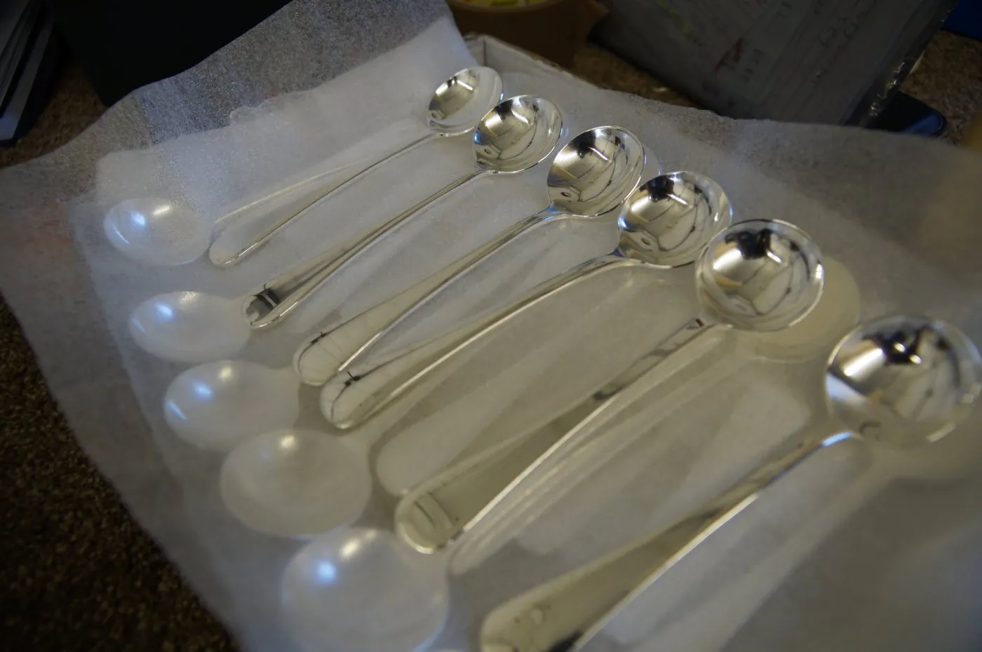 Freshly re-plated soup spoons laid out on packing foam, ready to return